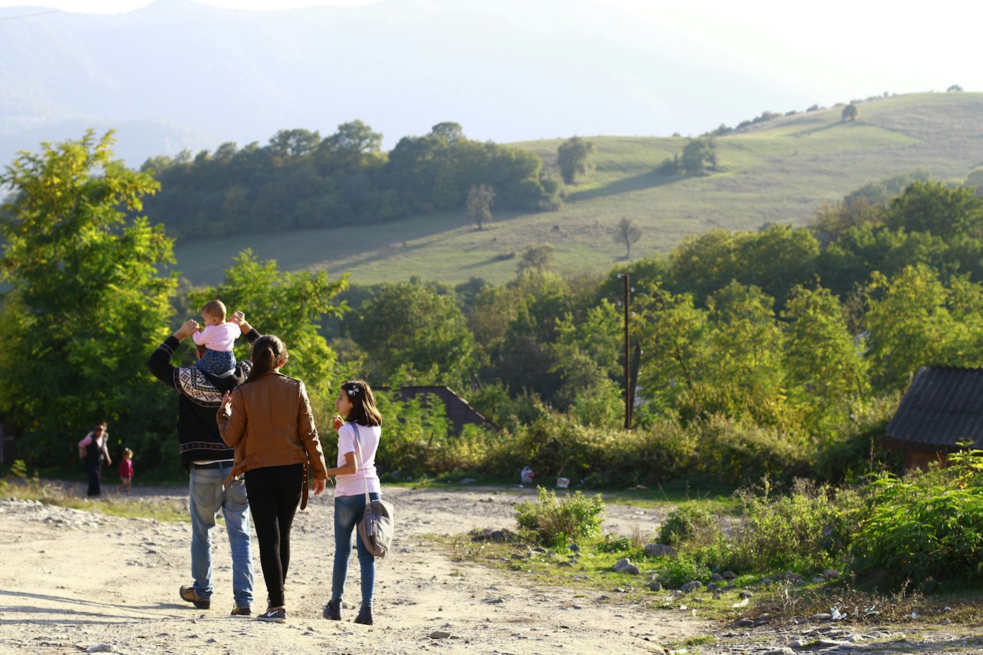 Famille avec un enfant sur les épaules marchant sur un chemin de campagne
